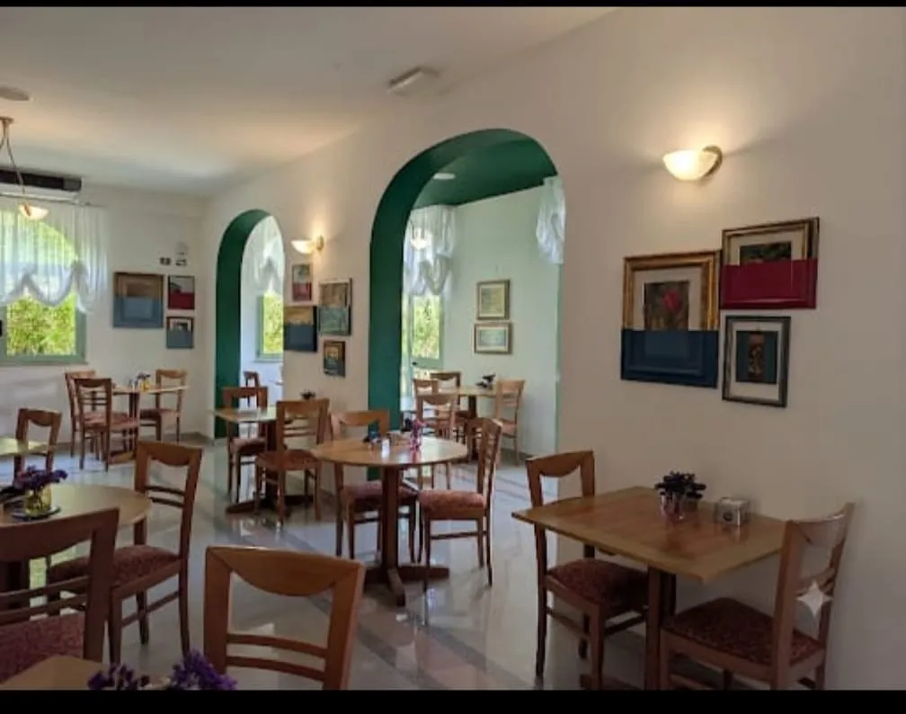 Sala colazioni dell'Hotel Dover Rooms & Coffee con archi verdi