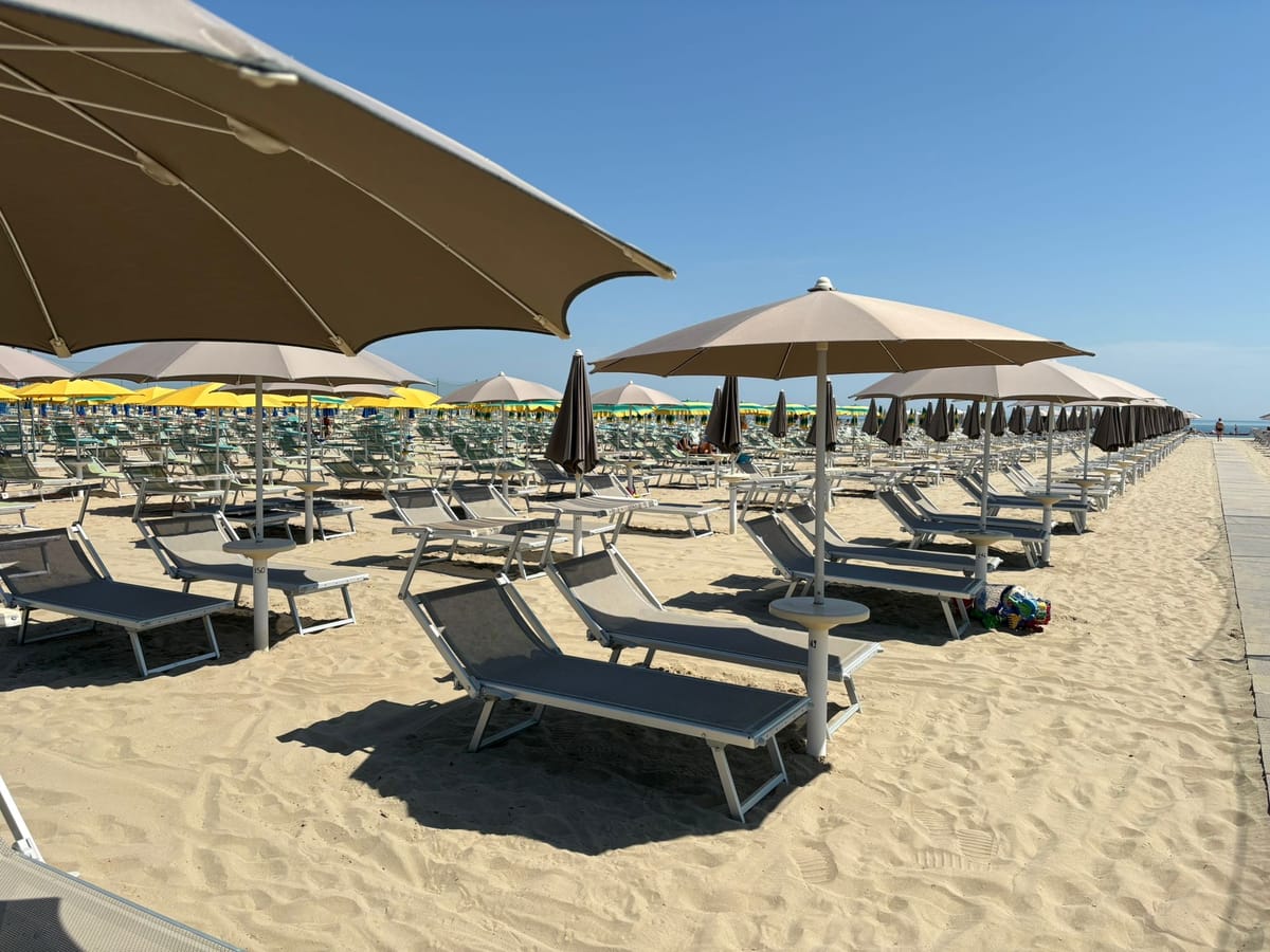 File ordinate di ombrelloni aperti e lettini sulla spiaggia del Bagno Dover 175 a Cervia