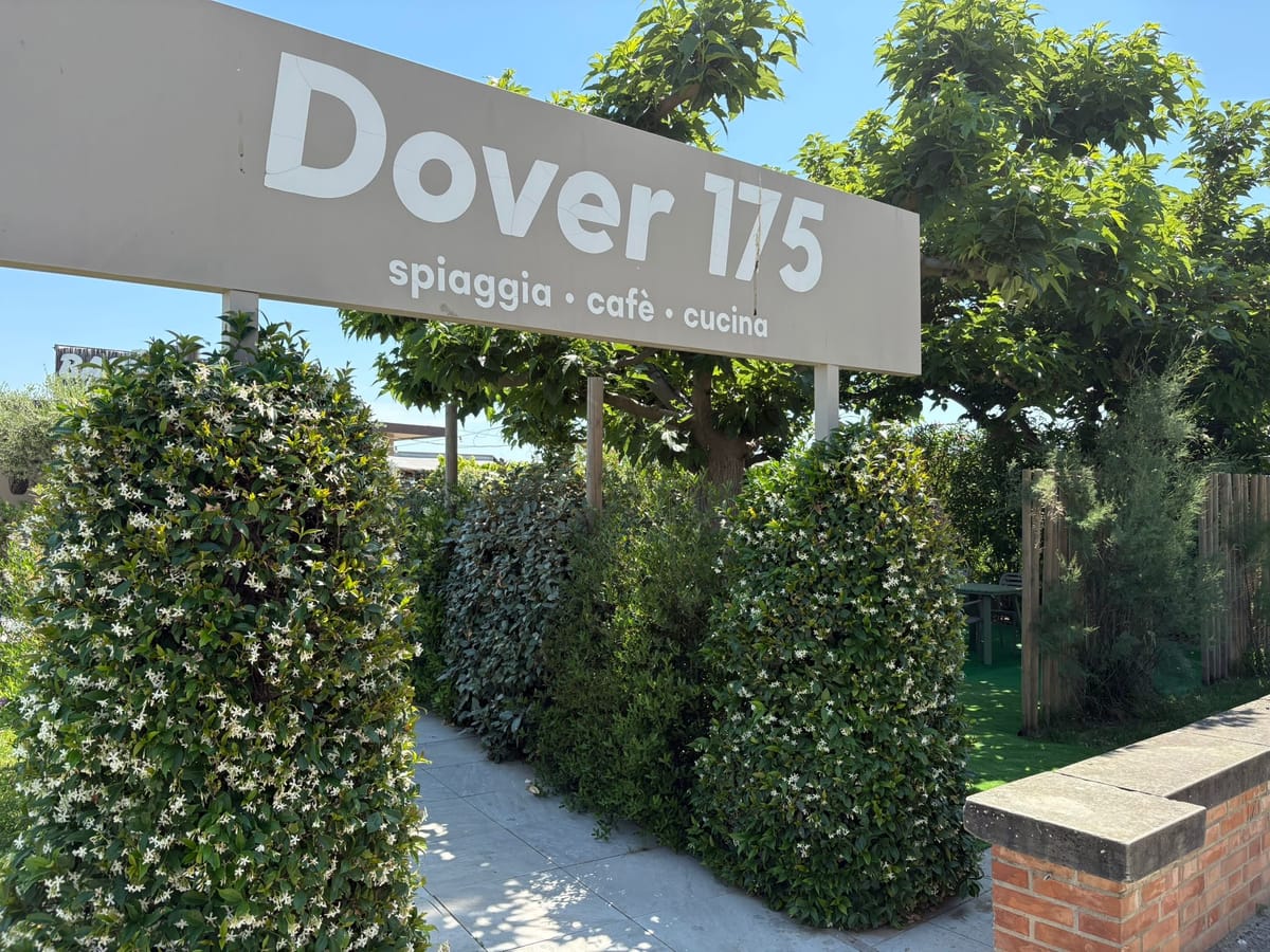 Insegna 'Dover 175 · spiaggia · caffè · cucina' all'ingresso del Bagno Dover con siepi di gelsomino in fiore